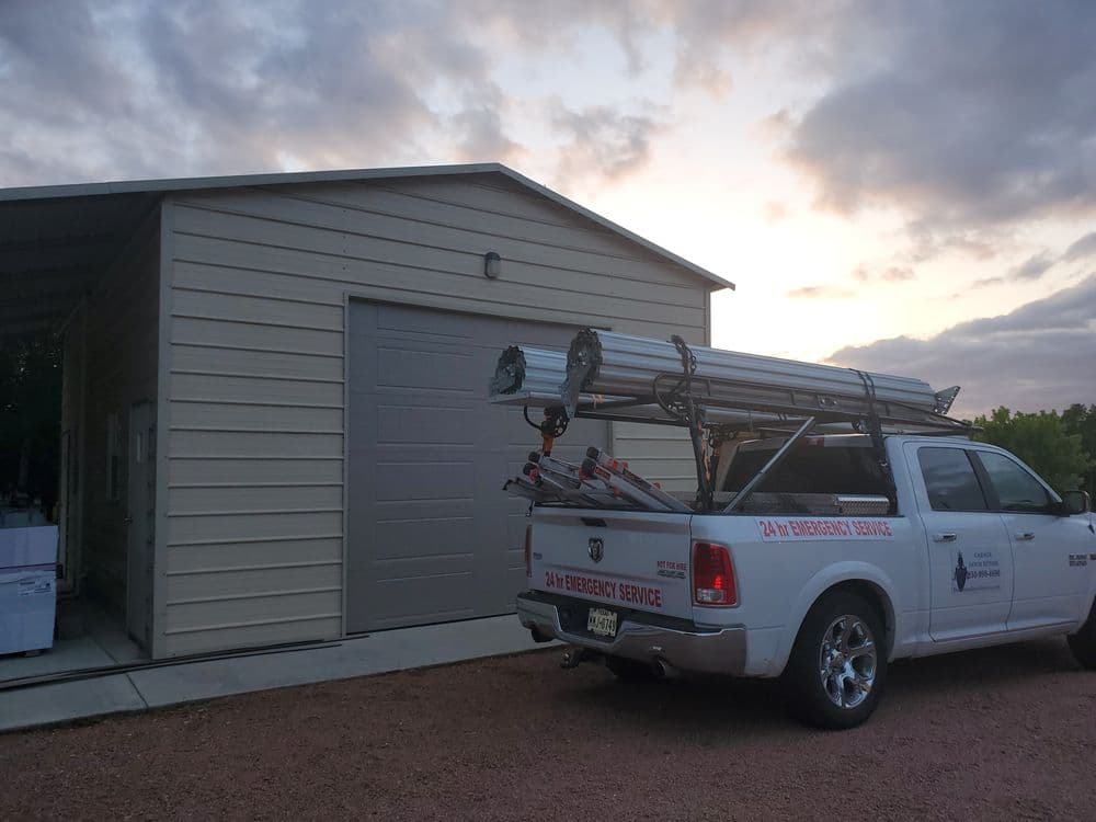 Emergency service truck with ladder parked outside a metal building at dusk.