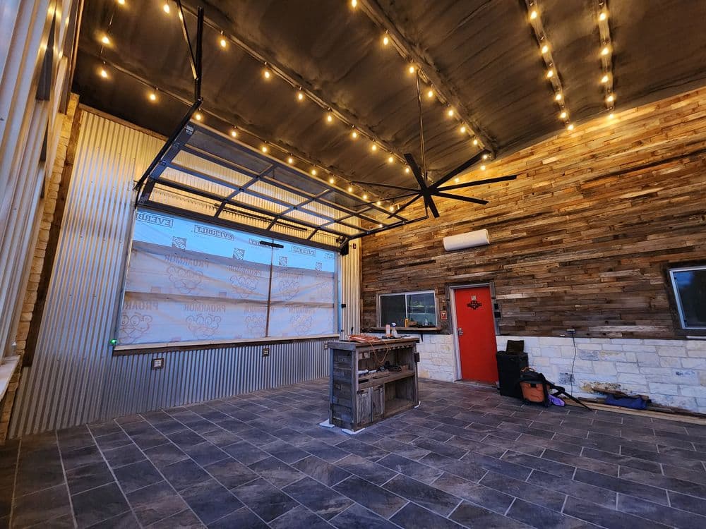 Modern indoor space with string lights, wooden accents, and a garage-style door.