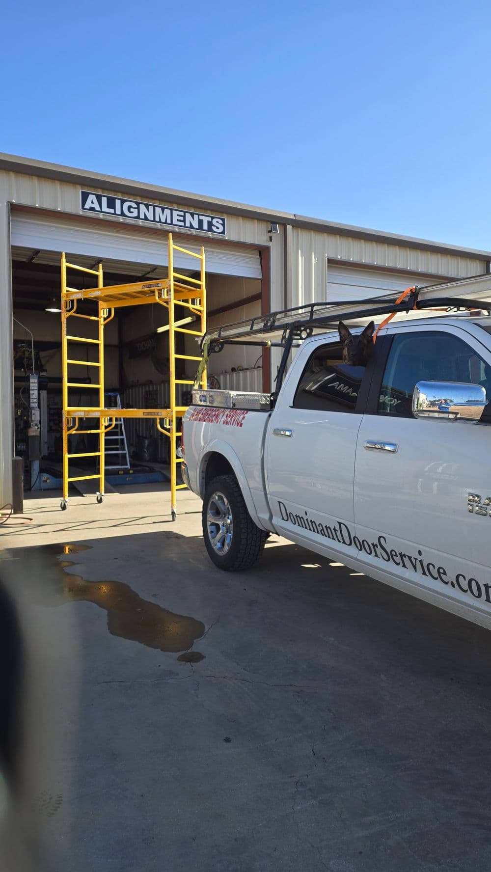 White truck parked outside an alignment service shop with scaffolding visible.