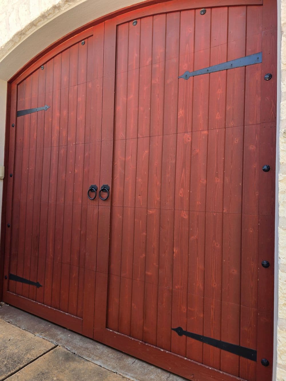 Elegant wooden double doors with iron accents and circular handles, set in a stone archway.