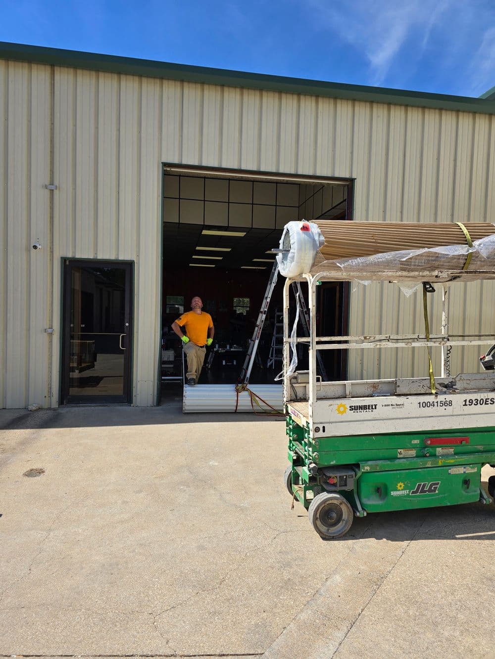 Construction worker near lift and building entrance, preparing for project tasks.