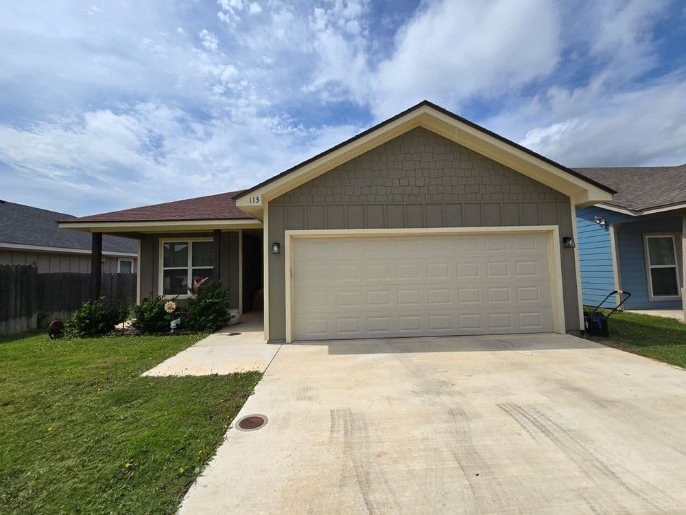 Single-story house with a garage, green lawn, and blue sky. Ideal for homebuyers and renters.