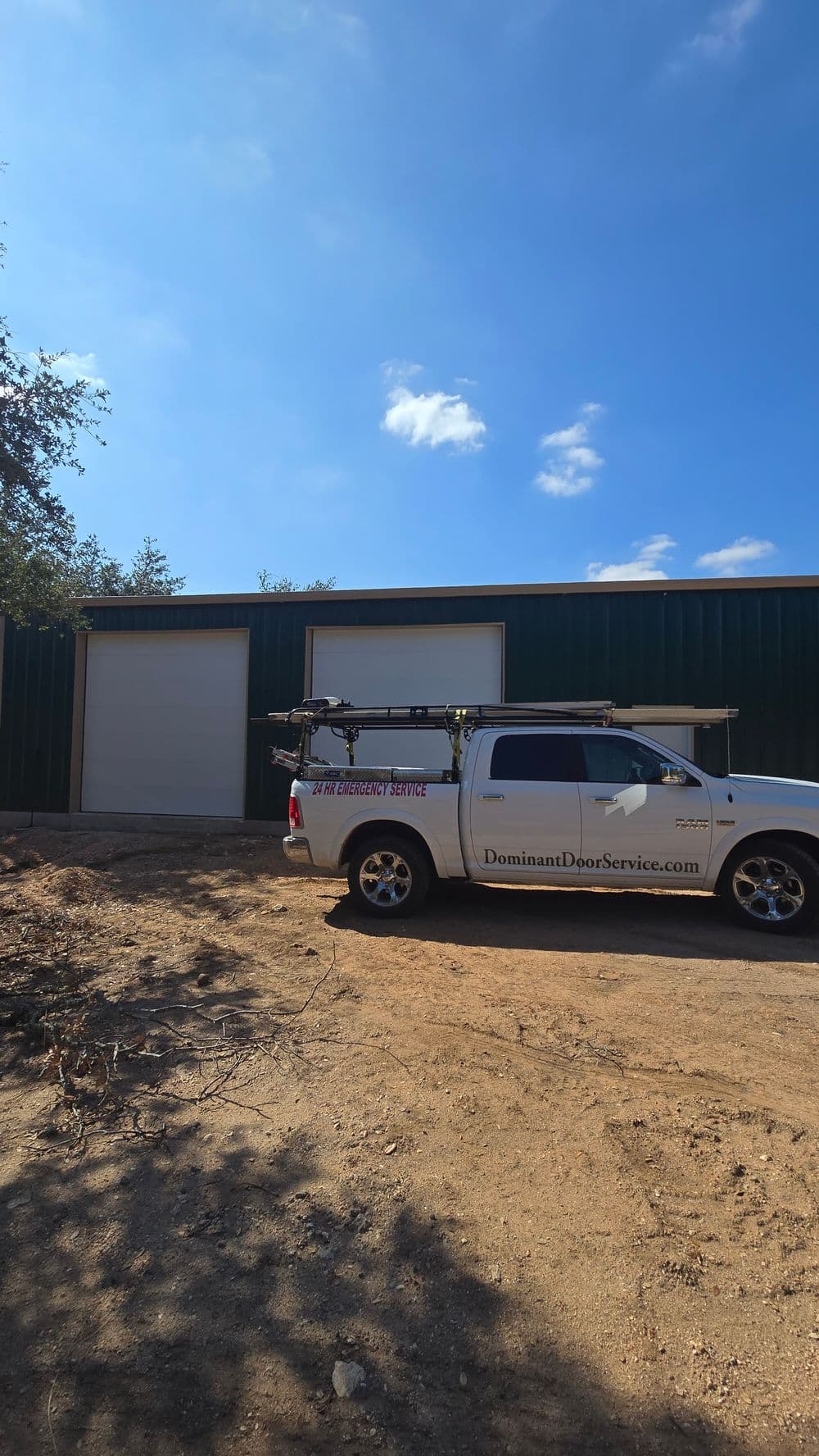 White service truck parked near a green metal building, promoting Dominant Door Service.