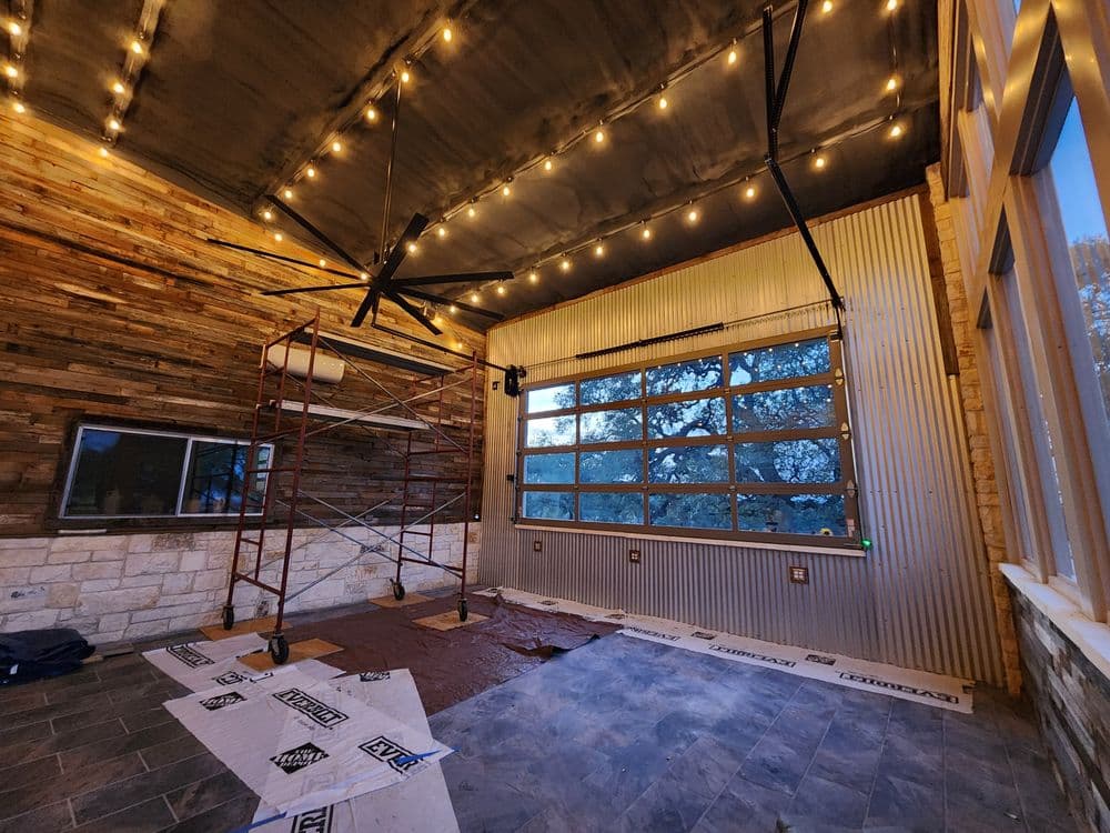 Renovated indoor space with wooden walls, large windows, scaffolding, and ambient lighting.