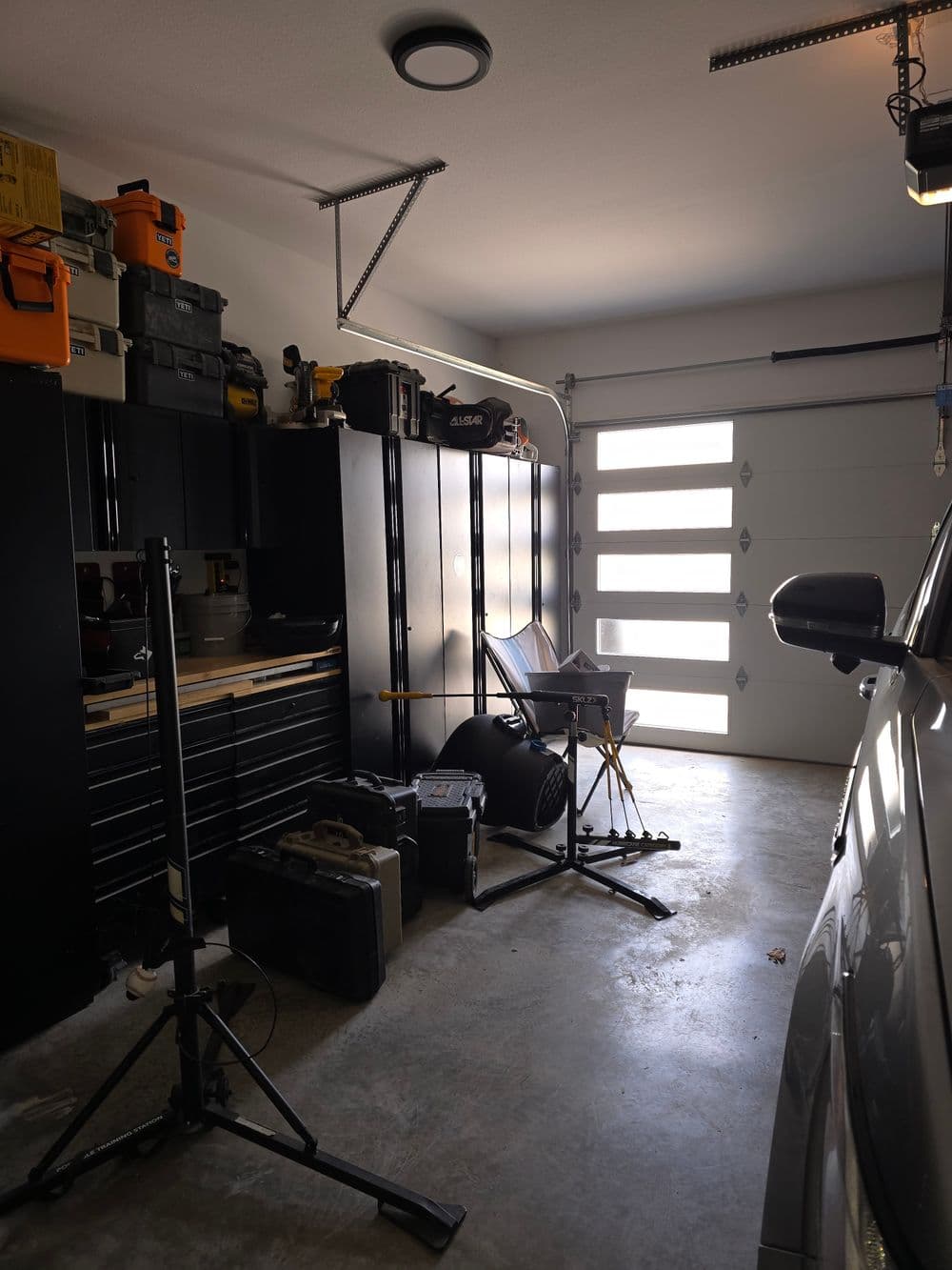 Spacious garage with organized tools, a workbench, and a parked car. Bright natural light enters.