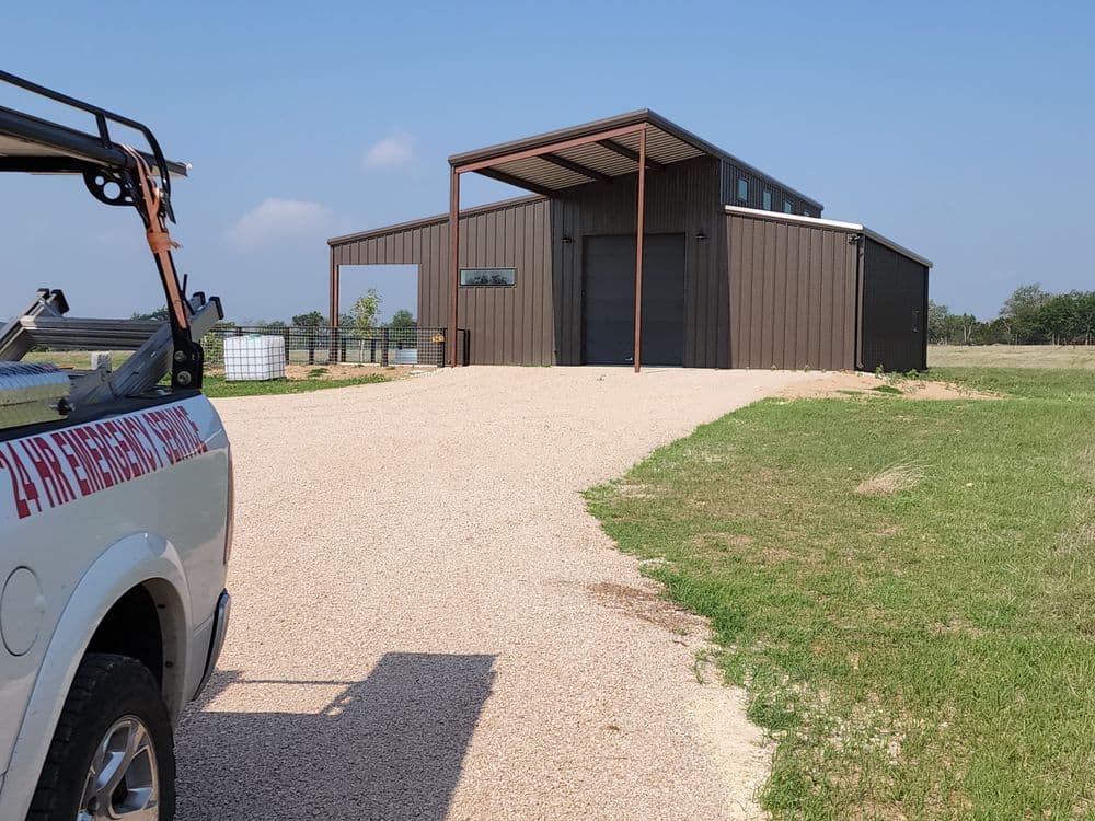 Modern metal building on a gravel driveway with a service vehicle in the foreground.