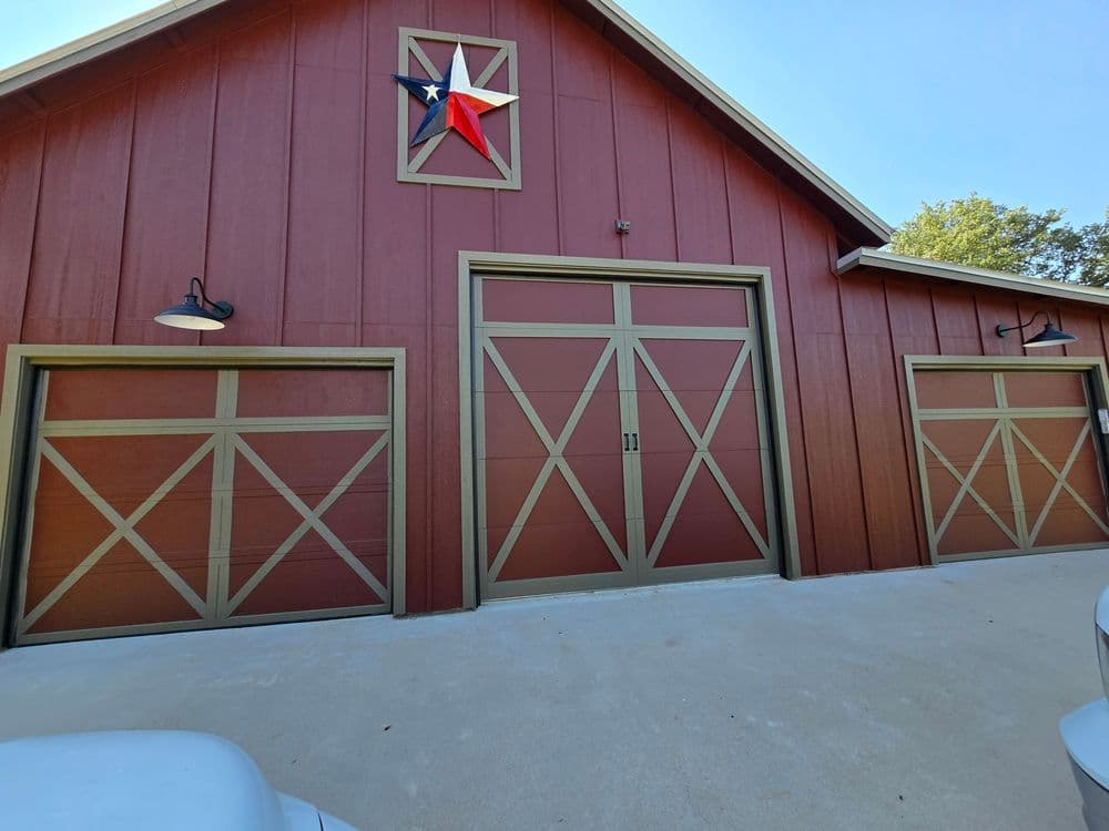 Red barn-style garage with Texas star, three garage doors, and side lighting.