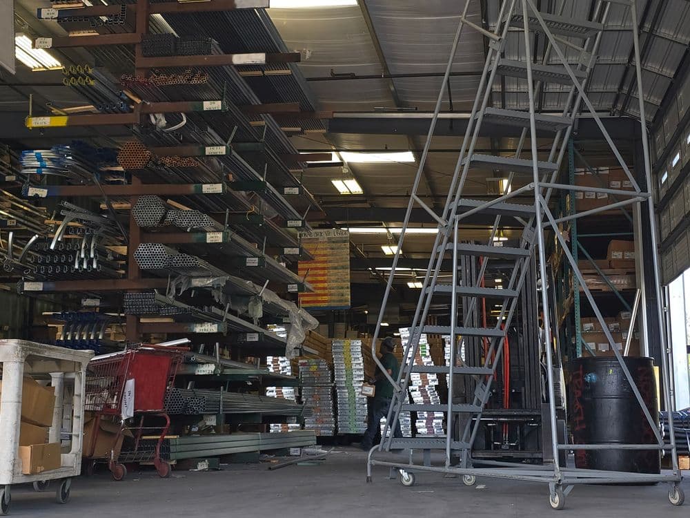 Interior of a storage facility with stacked metal materials and a mobile storage ladder.