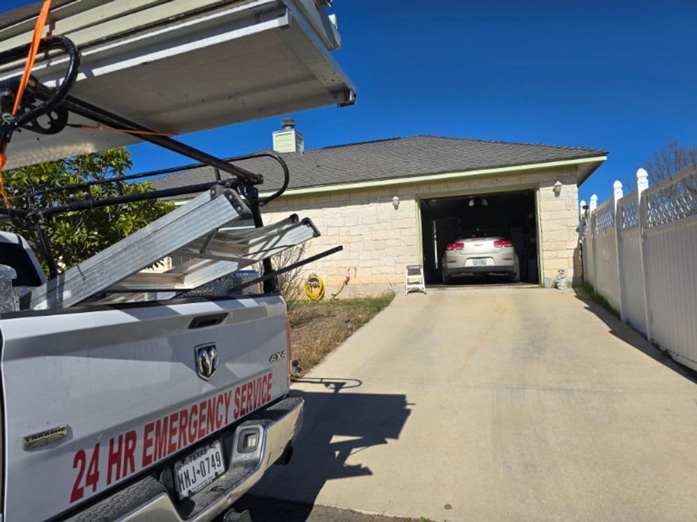 Emergency service vehicle parked in driveway of house with garage door partially open.