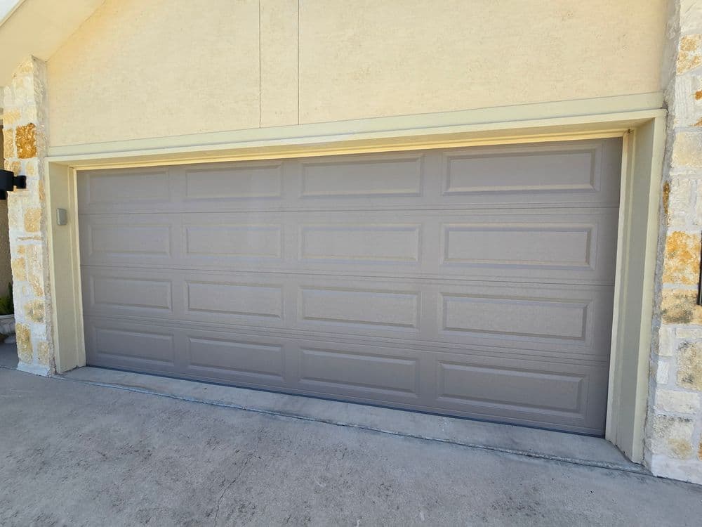 Modern gray garage door on a stylish home exterior with stone accents.