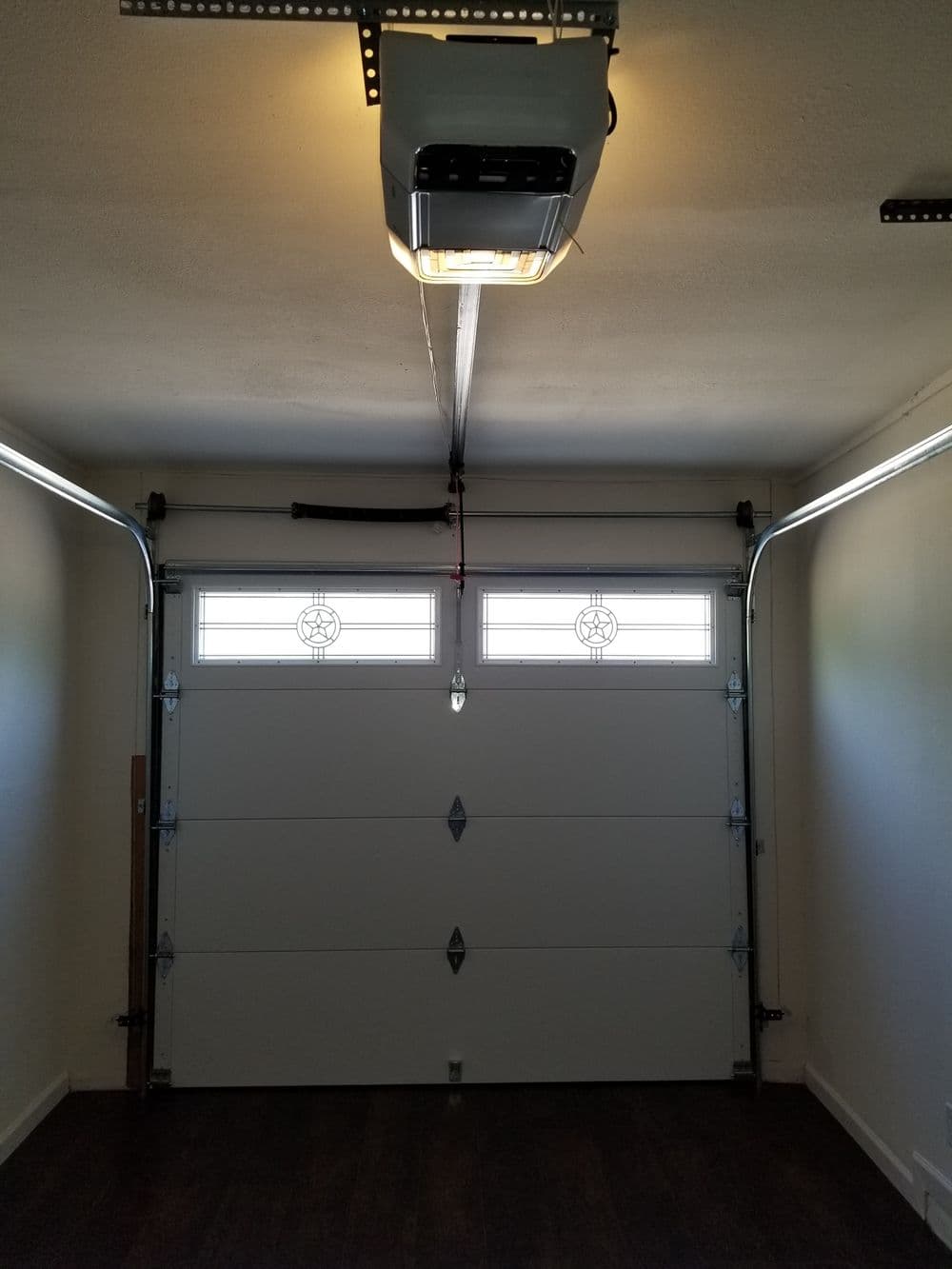 Interior view of a garage with a modern door and ceiling-mounted heater. Bright lighting.