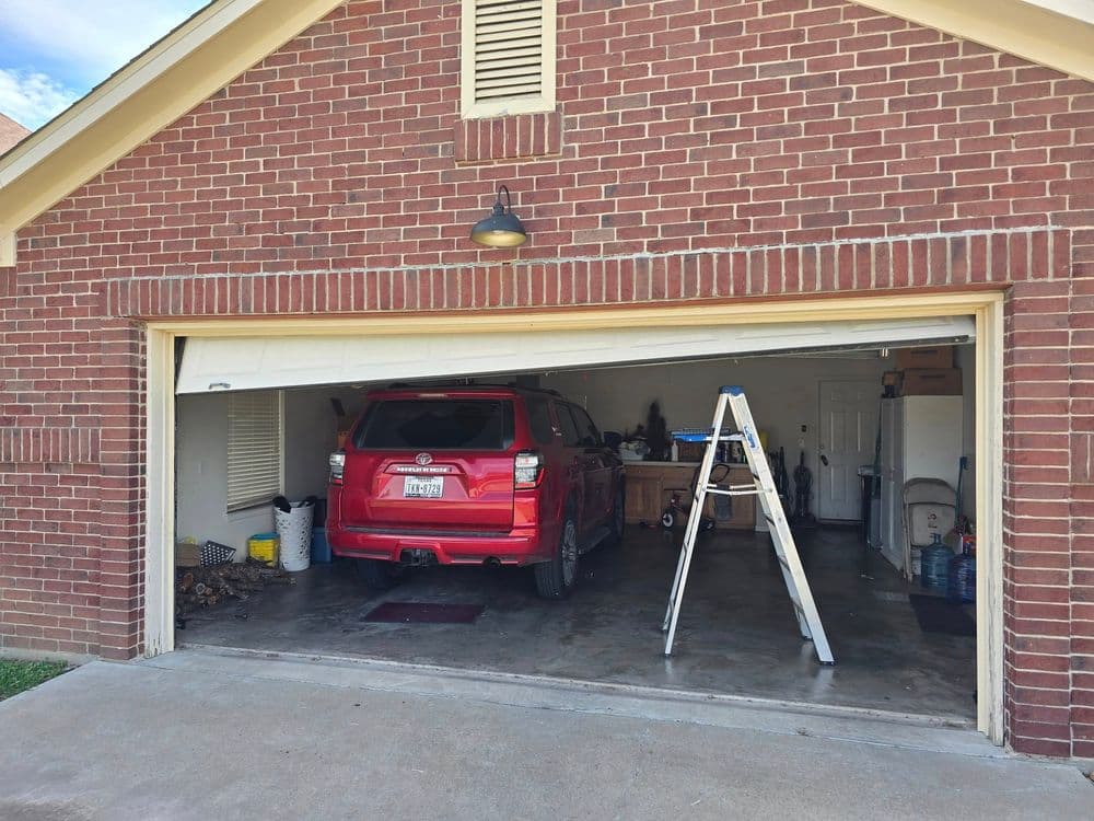Red SUV parked in a garage with tools, a ladder, and storage items visible.