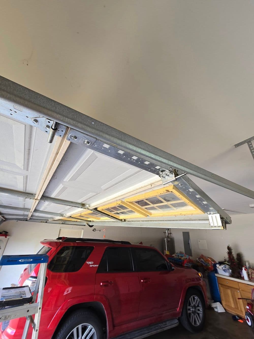 Red SUV parked in garage with partially opened garage door and tools in background.
