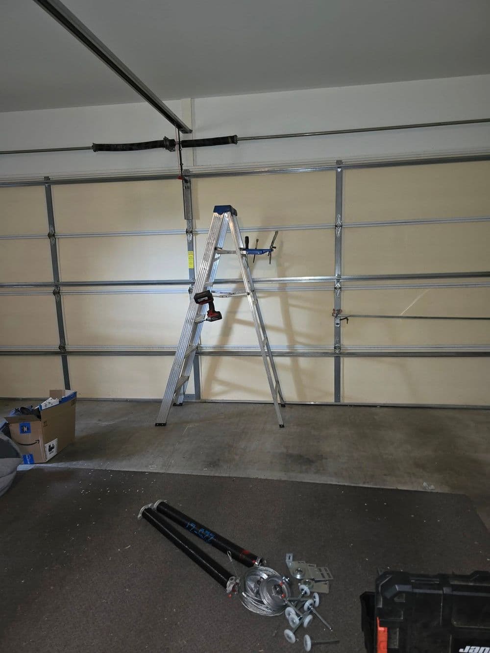 Ladder in a garage with tools and storage boxes, showcasing a workspace setup.